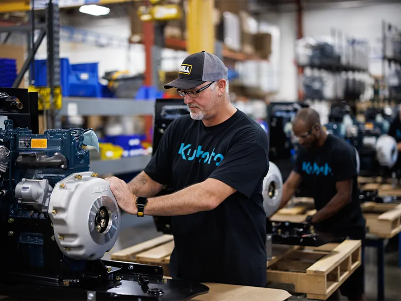 Kubota engine distributor employees working on engines in a factory setting.