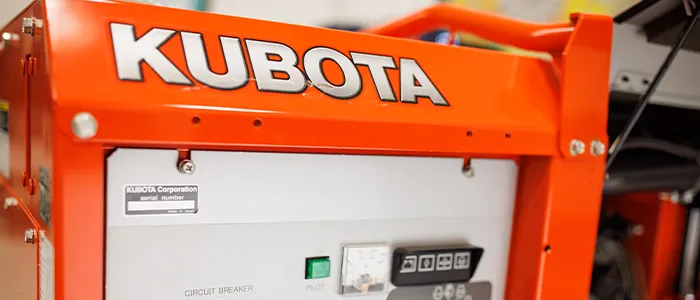Orange Kubota generator with serial number label at top left corner.